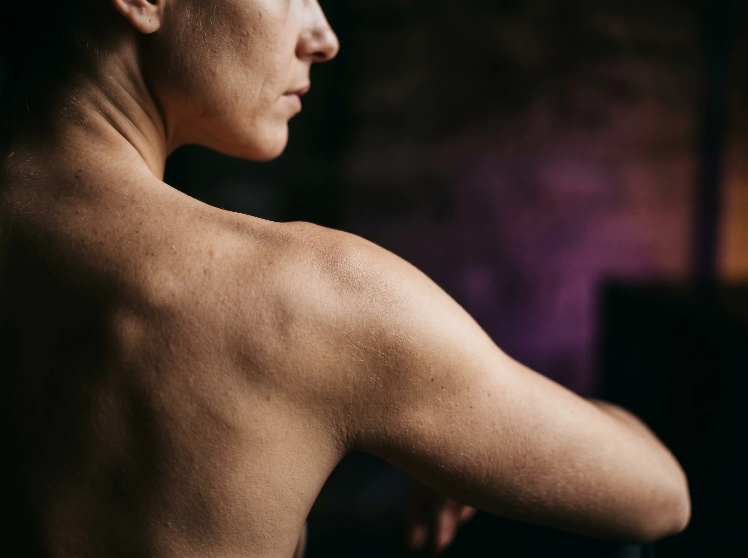 Close-up of bare shoulder and upper arm skin in moody side lighting